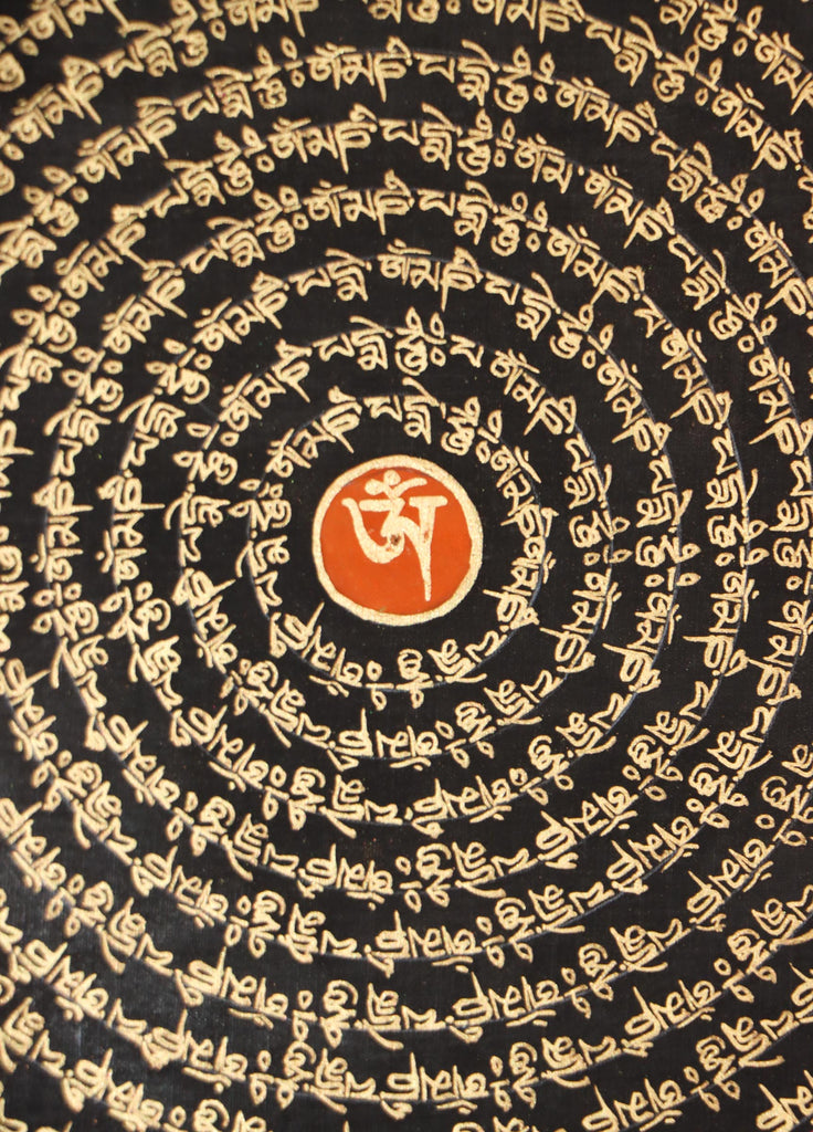 close up view of Mantra Mandala Thangka with om symbol scripted in its center .