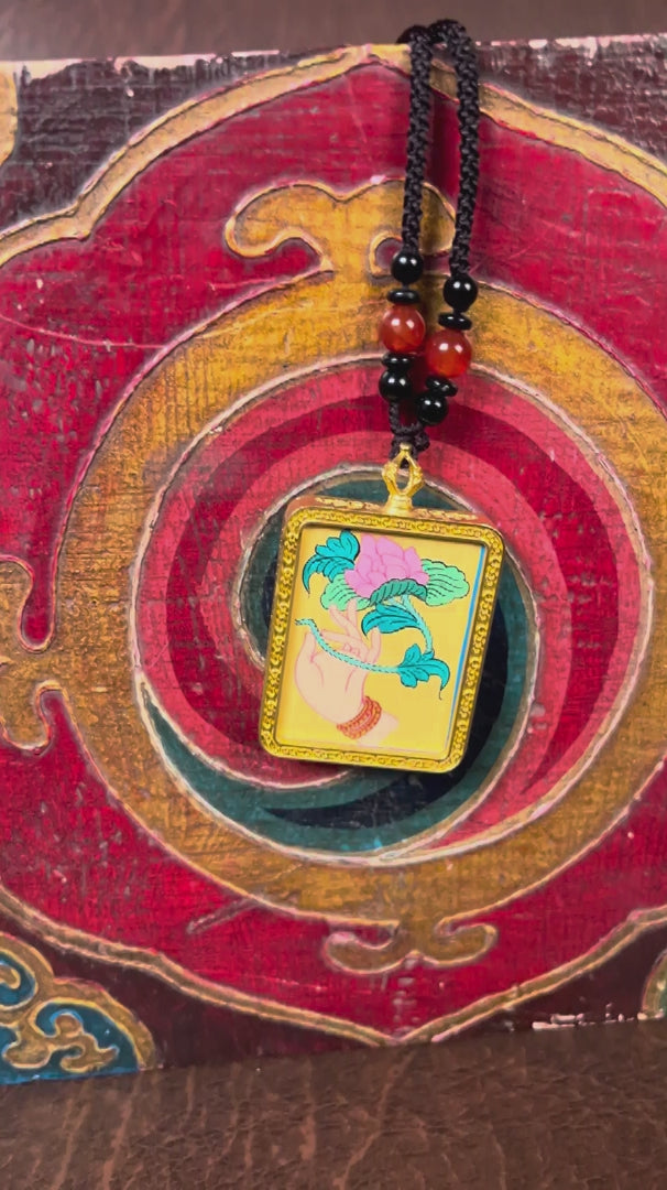 Hand holding lotus Ghau Thangka locket with hand-painted symbolic artwork inside traditional Himalayan amulet Nepal